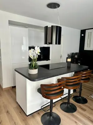a kitchen with a black counter with four chairs at Appartement neuf et rénové promenade des anglais in Nice