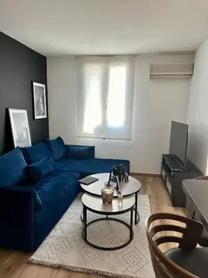 a living room with a blue couch and a table at Appartement neuf et rénové promenade des anglais in Nice