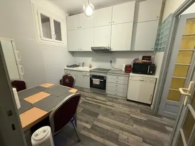 a kitchen with white cabinets and a table with chairs at Charming house near Center Nice with new air conditioner in Nice