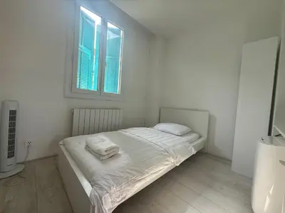 a white bedroom with a bed with two towels on it at Charming house near Center Nice with new air conditioner in Nice
