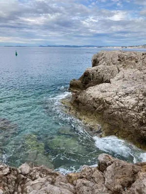 a body of water with rocks and a boat in the water at Wunderschöne Wohnung in Jugendstilvilla am Hafen in Nice
