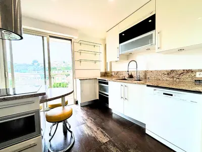 a kitchen with white cabinets and a table and a window at Le St Charles in Saint-Laurent-du-Var