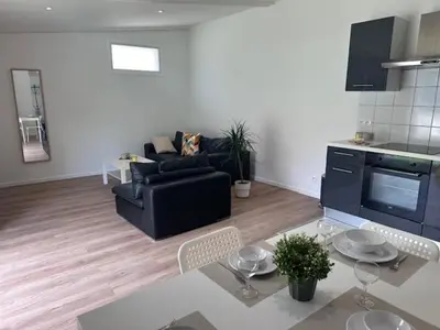 a living room with a black couch and a table at appartement au calme avec jardin privatif dans maison in Cagnes-sur-Mer