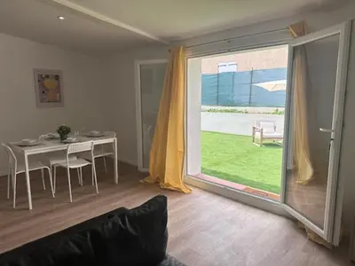 a living room with a table and a large window at appartement au calme avec jardin privatif dans maison in Cagnes-sur-Mer