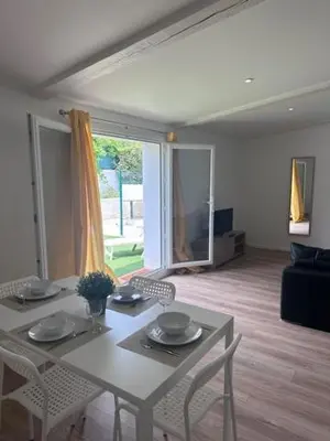 a living room with a table and chairs and a couch at appartement au calme avec jardin privatif dans maison in Cagnes-sur-Mer