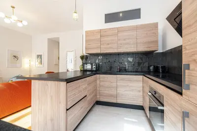 a kitchen with wooden cabinets and black counter tops at Soleil de la Buffa - Un joyau central à 3 min des plages in Nice