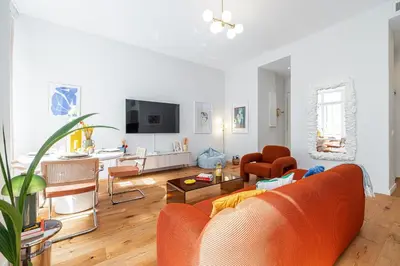 a living room with an orange couch and a table at Soleil de la Buffa - Un joyau central à 3 min des plages in Nice