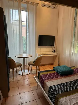 a room with two beds and a tv and a table at STUDIO dans Villa à Nice Ouest in Nice