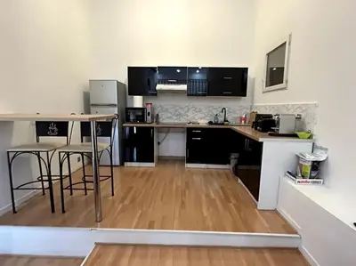 a kitchen with a table and chairs in a room at Charmant studio avec mezzanine in Nice