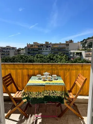 a table with two chairs and a table with cups and plates at Studio style vintage à Nice in Nice