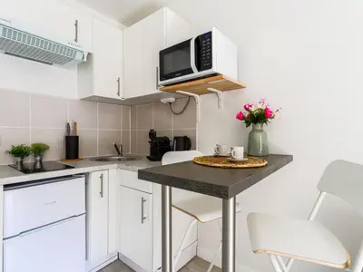 a kitchen with white cabinets and a table with a microwave at Studio Le Maréchal by Interhome in Nice