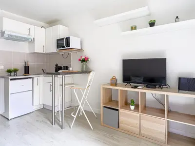 a kitchen with white cabinets and a desk with a tv at Studio Le Maréchal by Interhome in Nice