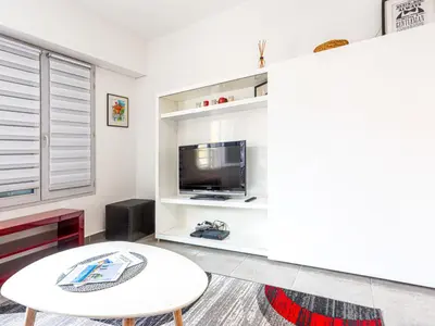a living room with a table and a tv at Apartment Jardin Pastorelli by Interhome in Nice
