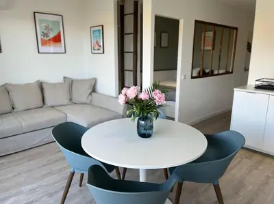 a white table with chairs and a vase of pink flowers at New apartment with swimming pool in Beaulieu-sur-Mer
