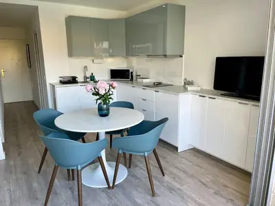 a kitchen with a white table and blue chairs at New apartment with swimming pool in Beaulieu-sur-Mer