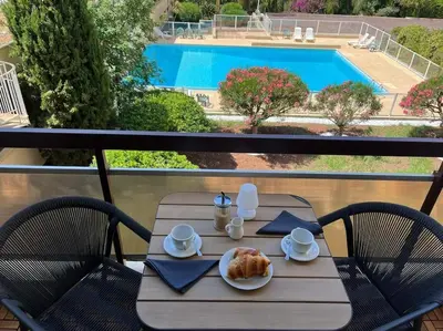 a table with a plate of food on a balcony with a pool at New apartment with swimming pool in Beaulieu-sur-Mer