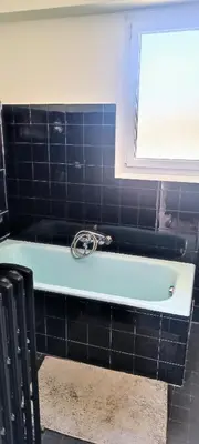 a blue bath tub in a black tiled bathroom at Chambre vue Nice & mer in Nice