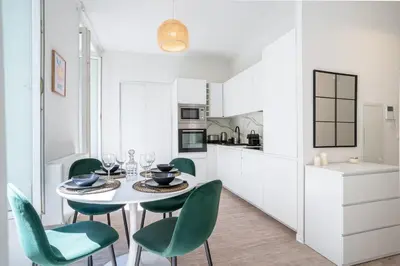 a white kitchen with a table and green chairs at 06BZ - Modern apartment in the heart of the port in Nice