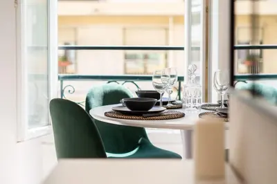a table with green chairs and a table with wine glasses at 06BZ - Modern apartment in the heart of the port in Nice