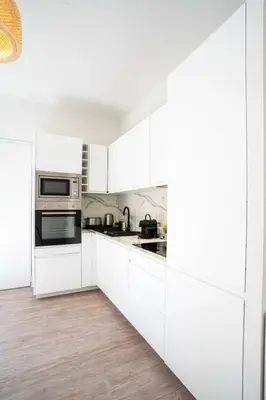 a white kitchen with white cabinets and appliances at 06BZ - Modern apartment in the heart of the port in Nice