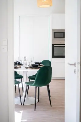 a white kitchen with a table and green chairs at 06BZ - Modern apartment in the heart of the port in Nice
