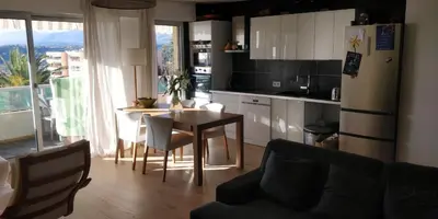 a kitchen and dining room with a table and a refrigerator at Chez Gaël, vue mer, piscine, 3chb in Nice
