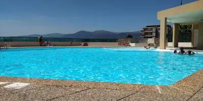 a large blue swimming pool with people in it at Chez Gaël, vue mer, piscine, 3chb in Nice