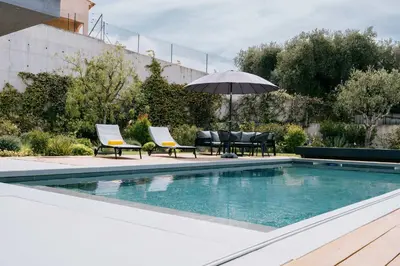 a swimming pool with two chairs and an umbrella at Prestigieuse Villa De Crémat Nice in Nice