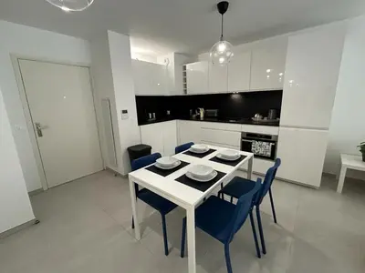 a white kitchen with a white table and blue chairs at Fabron Hills By Avecoeur in Nice