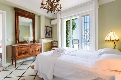a bedroom with a large white bed and a mirror at ROMANTIC VILLA VI4412 By Riviera Holiday Homes in Villefranche-sur-Mer