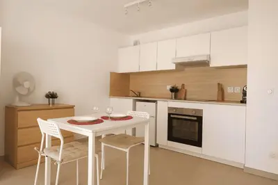 a kitchen with white cabinets and a table with a plate on it at Charming 23 m studio near the sea in Nice