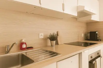 a kitchen with white cabinets and a sink at Charming 23 m studio near the sea in Nice