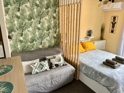 a small bedroom with a bed and a table at Palm Leaf Studio Nice in Nice