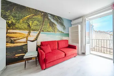 a red couch in a room with a palm tree mural at 2P hyper-centre Nice in Nice