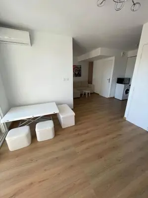 a living room with white walls and wooden floors at Appartement avec piscine in Saint-Laurent-du-Var