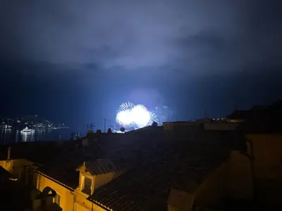 a firework display in the sky over roofs at night at The Seaside Serenity -NEW AC equipped - Calm with Bay View - Heart of Villefranche in Villefranche-sur-Mer