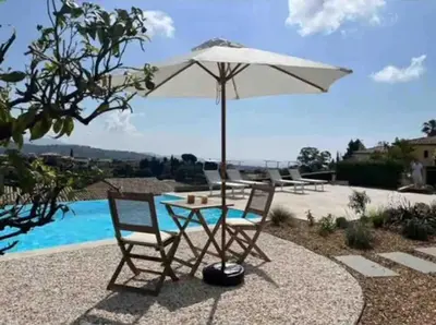 a table and chairs with an umbrella next to a pool at DOMAINE LOU BEL AZUR - Harmonie in Saint-Laurent-du-Var