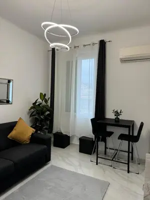 a living room with a black couch and a piano at Newly refurbished studio in Nice