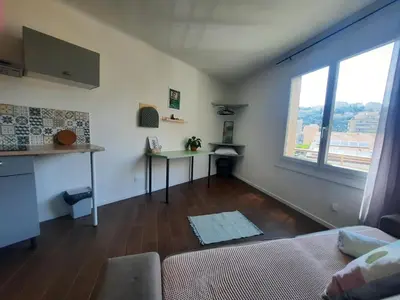a living room with a couch and a table and a window at La Chambre 3, Climatisée AC, Cuisine privée, Calme in Nice