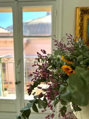 a vase with flowers in front of a window at Superbe duplex entre le Vieux Nice et la Prom in Nice
