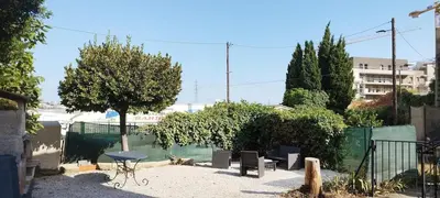 a patio with a table and chairs and a tree at Appartement 4 p neuf dans haut de villa , clim, parking, jardin in Saint-Laurent-du-Var