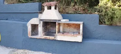 a brick oven sitting on the side of a blue wall at Appartement 4 p neuf dans haut de villa , clim, parking, jardin in Saint-Laurent-du-Var