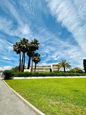 a park with palm trees in front of a building at Studio idéalement situé résidence front de mer in Saint-Laurent-du-Var
