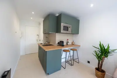 a kitchen with green cabinets and a counter with stools at Studio idéalement situé résidence front de mer in Saint-Laurent-du-Var