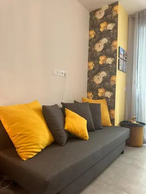 a couch with yellow and grey pillows in a room at Studio Coeur Delille FSHH in Nice