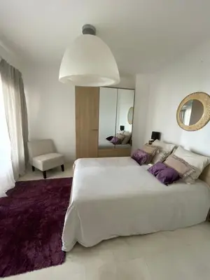 a white bedroom with a large bed and a mirror at face à la mer in Cros-de-Cagnes