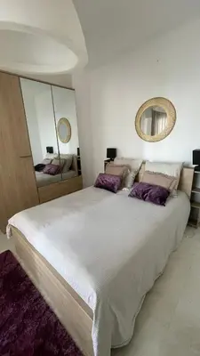 a bedroom with a large white bed with purple pillows at face à la mer in Cros-de-Cagnes
