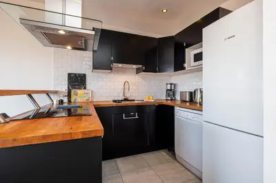a kitchen with black cabinets and a wooden counter top at Open Sky Terrace Lage 1 Bdr & Parking in Nice