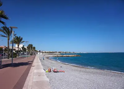 a group of people laying on a beach next to the ocean at La chambre de Cleron in Saint-Laurent-du-Var