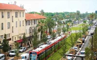 a red train on a city street with cars at Cosy flat 250m from beach in Nice